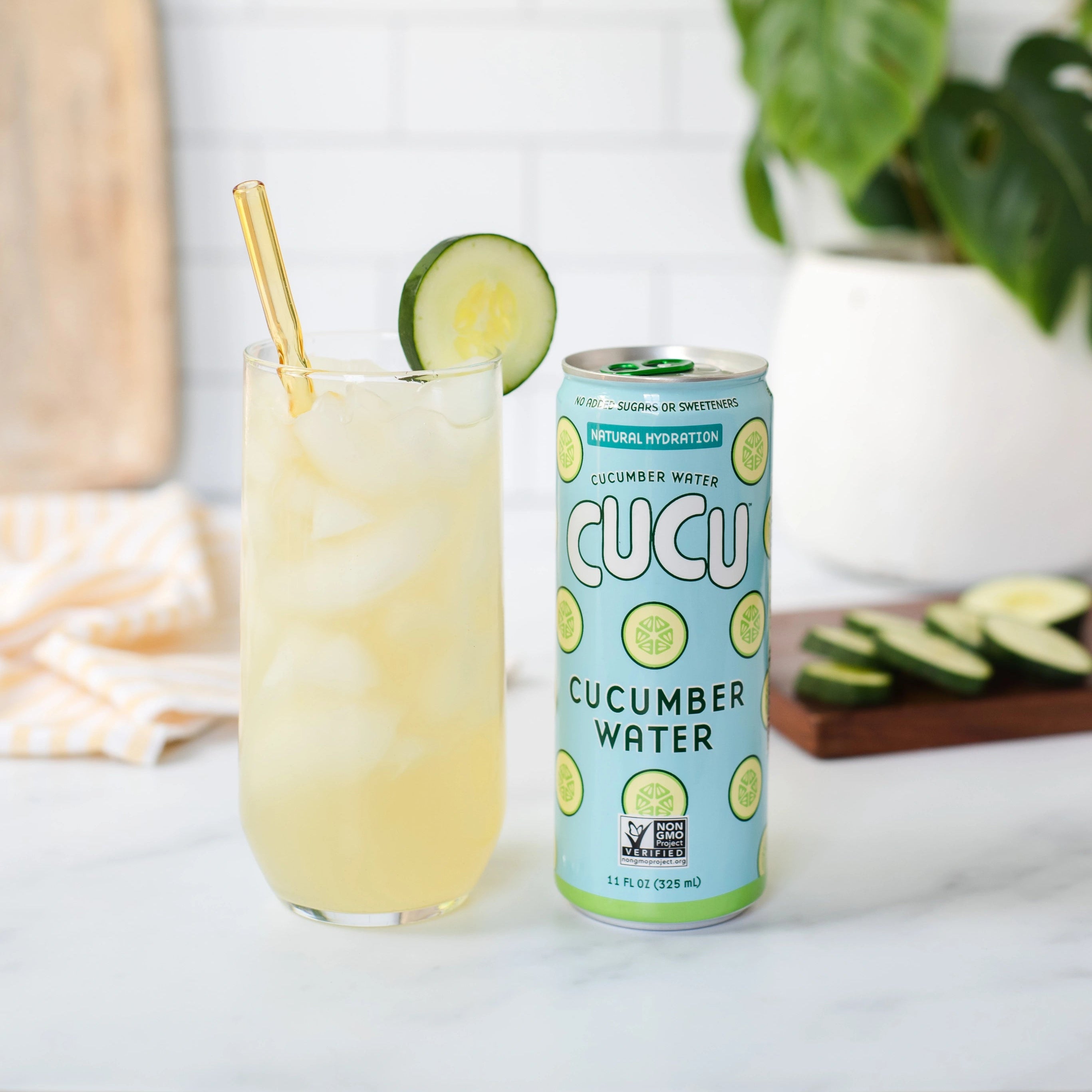CUCU cucumber water can with a glass of lemonade and cucumber slices on a white surface.